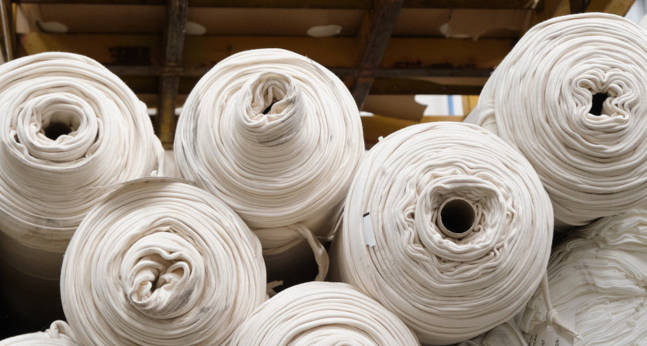 Rolls of surplus fabric stored on warehouse shelving, ready for resale on Circular Sourcing